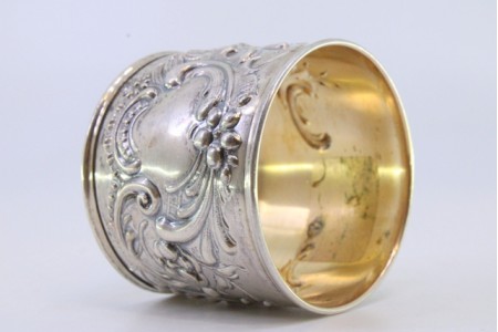 Argola de guardanapo em prata com motivos florais relevados envolvendo cartela para monograma.